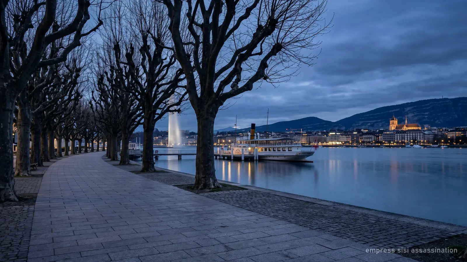 Une promenade déserte au bord du lac à Genève au crépuscule, avec un bateau à aubes amarré au loin