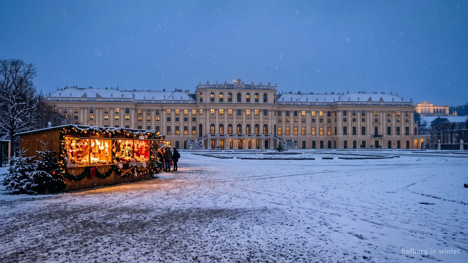 A Viennese palace facade under light snow at dusk, with warm window light
