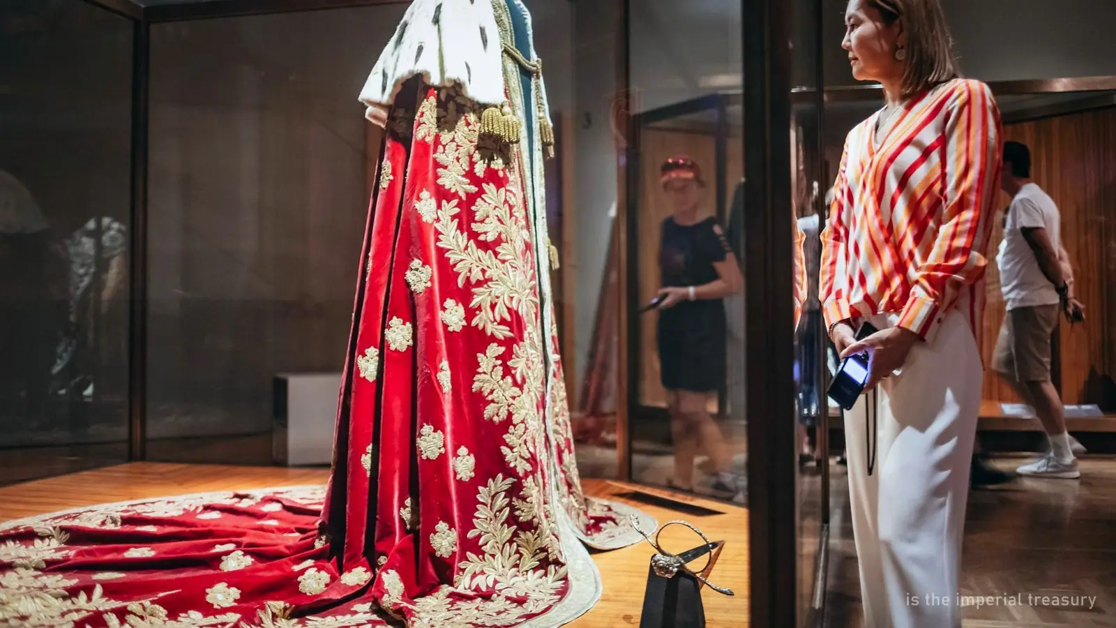 A red coronation robe displayed in a case in the Imperial Treasury, Vienna — photo from the booking listing