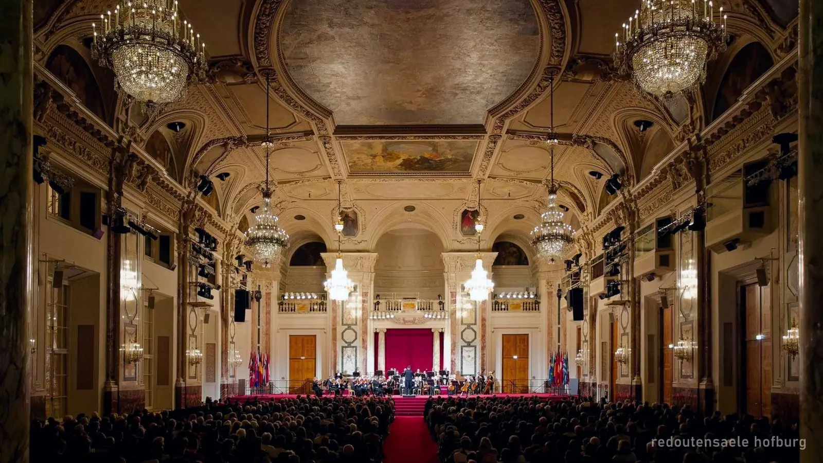 Ein Prunksaal der Hofburg in Wien mit Publikum bei einem Konzert, Foto aus dem Buchungsangebot