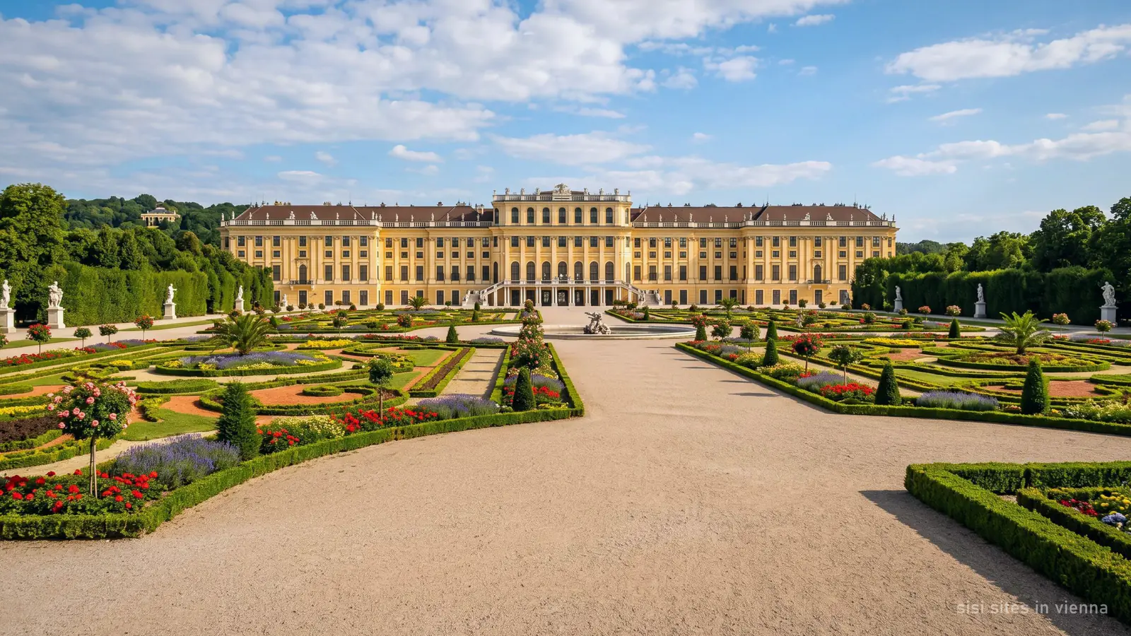 Ein prächtiges Barockschloss in Wien hinter formalen Parterregärten im Sommer