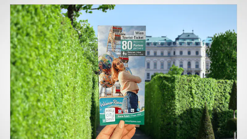 A visitor holding a Vienna sightseeing brochure beside clipped hedges — photo from the booking listing